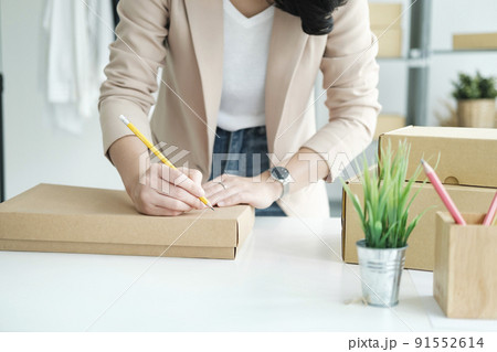 Start up small business owner writing address on cardboard box a. Start up small business owner writing address on cardboard box a. 91552614
