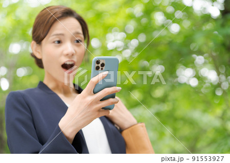 スマホを持つ女性　新緑 91553927