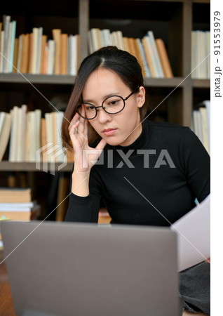 Female journalist focused reading and working on laptop 91553979