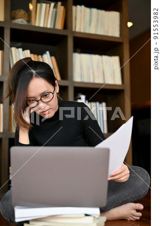 Focused young asian female freelancer or writer concentrated reading some content on laptop Focused young asian female freelancer or writer concentrated reading some content on laptop 91553982