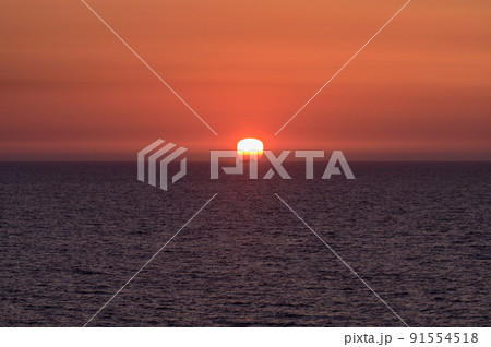 水平線に沈む夕日と沖を行く船の風景 水平線に沈む夕日と沖を行く船の風景 91554518