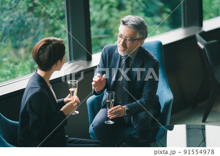 ラウンジでシャンパンを飲むシニア経営者と秘書 ラウンジでシャンパンを飲むシニア経営者と秘書 91554978