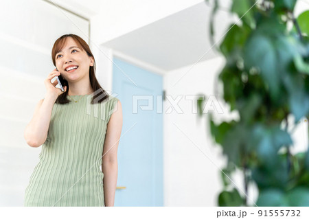 リビングで電話をする若い女性 白緑 リビングで電話をする若い女性 白緑 91555732