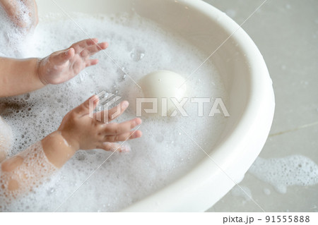 close up baby girl plays bubble in the water while bathing close up baby girl plays bubble in the water while bathing 91555888