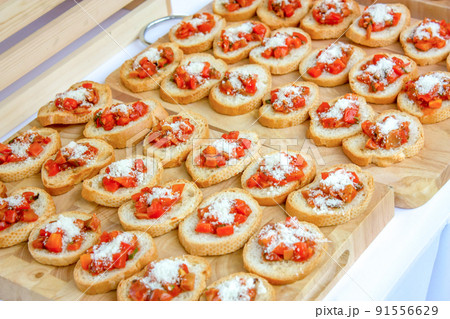 Baked slided French breads are arranged on the wood Butcher, topping by cheese and cooked tomato cube., Read to serve. 91556629