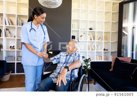 Biracial female health worker supporting caucasian senior man sitting on the wheelchair Biracial female health worker supporting caucasian senior man sitting on the wheelchair 91561005