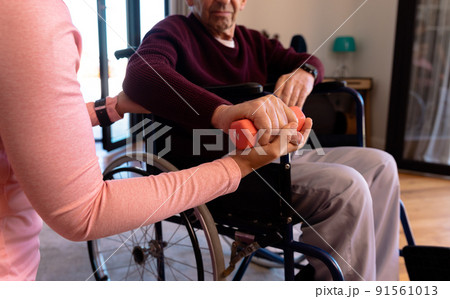 Mid section of female physiotherapist helping caucasian senior man to do exercise with dumbbells Mid section of female physiotherapist helping caucasian senior man to do exercise with dumbbells 91561013