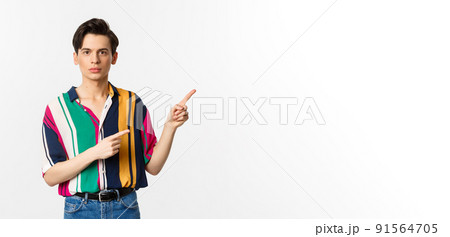 Portrait of young handsome man pointing fingers at upper right corner, showing logo, standing over white background 91564705