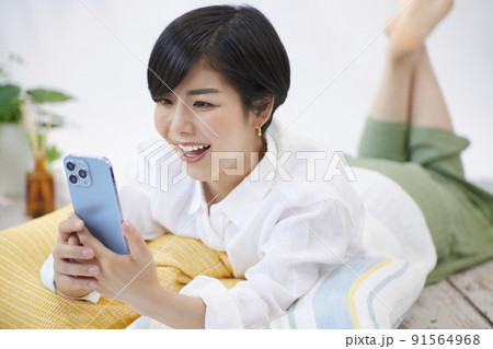 リビングでスマホを見る若い女性 リビングでスマホを見る若い女性 91564968