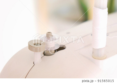 Winding threads on a bobbin on sewing machine. Winding threads on a bobbin on sewing machine. 91565015