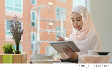 Muslim woman business owner checking product purchase order on digital tablet. Online selling, e-commerce concept 91567307