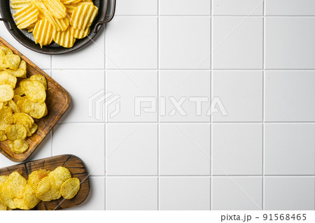 Honey BBQ Flavored Potato Chips on white ceramic squared tile table background, top view flat lay, with copy space for text Honey BBQ Flavored Potato Chips on white ceramic squared tile table background, top view flat lay, with copy space for text 91568465