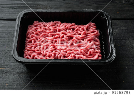Fresh minced meat in plastic box packaging tray, on black wooden table background 91568793