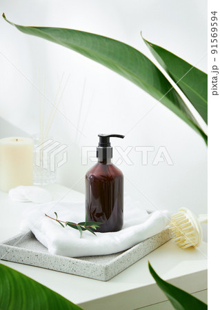 Cosmetics product and cotton towels, cottons pad with green plant on white table inside a bathroom background ceramic. Cosmetics product and cotton towels, cottons pad with green plant on white table inside a bathroom background ceramic. 91569594