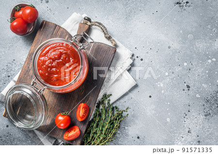 Homemade red tomato sauce with basil in glass jar. Gray background. Top view. Copy space Homemade red tomato sauce with basil in glass jar. Gray background. Top view. Copy space 91571335