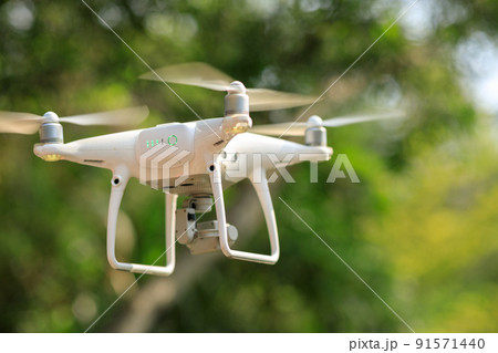 White drone with camera flying in spring tropical forest White drone with camera flying in spring tropical forest 91571440