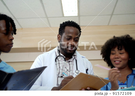 Group of American - African ethnicity medical student or intern doctor in general hospital making a discussion together about symptomatic treatment, happy medical student talking. Healthcare worker. Group of American - African ethnicity medical student or intern doctor in general hospital making a discussion together about symptomatic treatment, happy medical student talking. Healthcare worker. 91572109