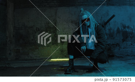 girl with dreadlocks and katanas in red glasses posing against a neon brick wall 91573075