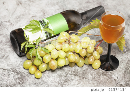 White wine bottle with bunch of grapes, glass on a dark background, top view. 91574154