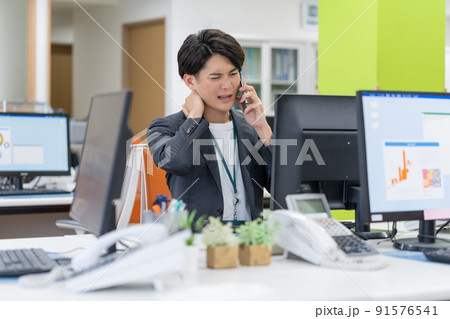 オフィスでスマホで会話する困った顔の若いビジネスマン 91576541