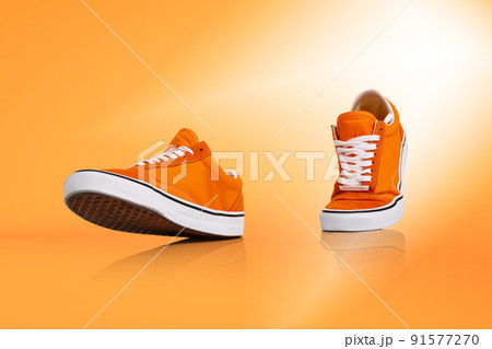 Modern unisex footwear, sneakers isolated on orange background. Fashionable stylish sports casual shoes. Creative minimalistic layout with footwear. 91577270