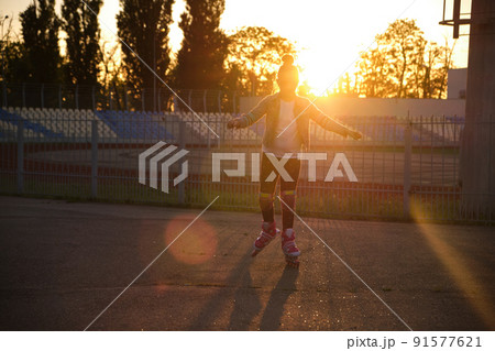 Girl riding roller skates in the park Girl riding roller skates in the park 91577621