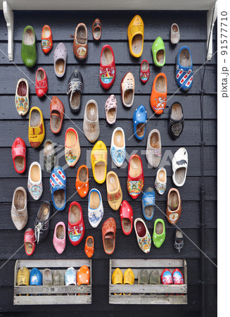 Many multicolored vintage Dutch Klomp shoes on black wood panel background 91577710