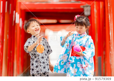 夏祭り、水風船を持つ浴衣姿の女の子と甚平姿の男の子の写真素材