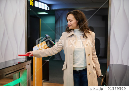 Woman passenger scanning info on smartphone by placing it over scanner QR-codes reader at check-in counter, entering VIP lounge at airport terminal Woman passenger scanning info on smartphone by placing it over scanner QR-codes reader at check-in counter, entering VIP lounge at airport terminal 91579599
