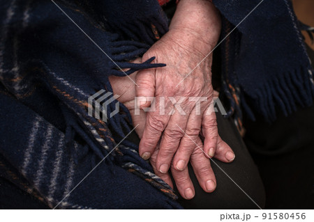 The hands of a mature 93-year-old grandmother with wrinkles lie on a cozy blanket at home. The concept of love and care. Slow movement 91580456