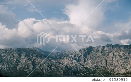 White cumulus clouds over the Kotor Bay mountain range 91580956