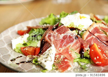 Delicious prosciutto salad with vegetables on plate, closeup 91583896