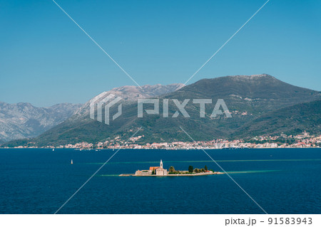 Island of Otocic Gospa in the bay against the backdrop of the town on the coast. Montenegro 91583943