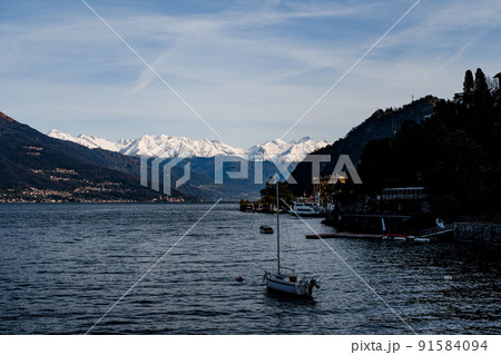 Sailing yacht sails on Lake Como past the coast of Varenna. Italy Sailing yacht sails on Lake Como past the coast of Varenna. Italy 91584094