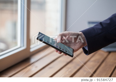 Closeup image of male hand holding smartphone with white blank screen. Man's hands with cellphone Closeup image of male hand holding smartphone with white blank screen. Man's hands with cellphone 91584727
