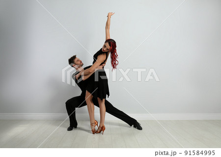 Beautiful young couple dancing near light wall 91584995