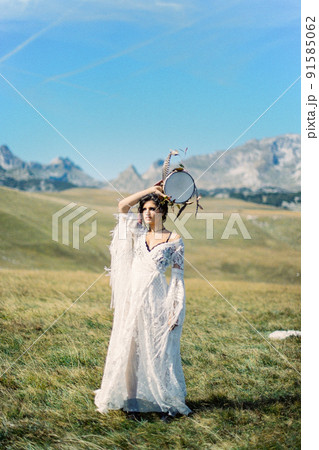 Girl with a tambourine in her hand stands in a green valley Girl with a tambourine in her hand stands in a green valley 91585062