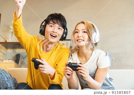 テレビゲームで遊ぶ若い男女 91585807