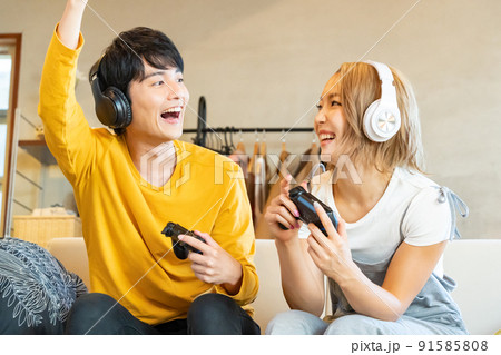 テレビゲームで遊ぶ若い男女 91585808