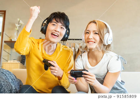 テレビゲームで遊ぶ若い男女 91585809