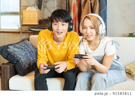 テレビゲームで遊ぶ若い男女 91585811