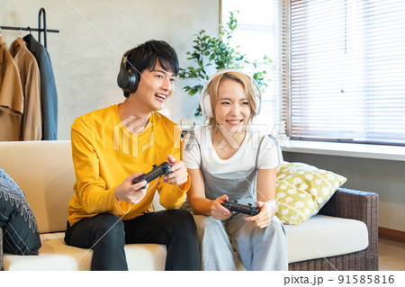 テレビゲームで遊ぶ若い男女 91585816