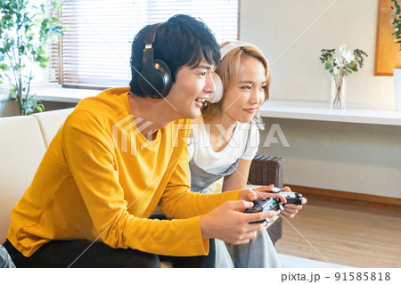 テレビゲームで遊ぶ若い男女 91585818