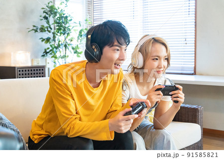 テレビゲームで遊ぶ若い男女 91585821