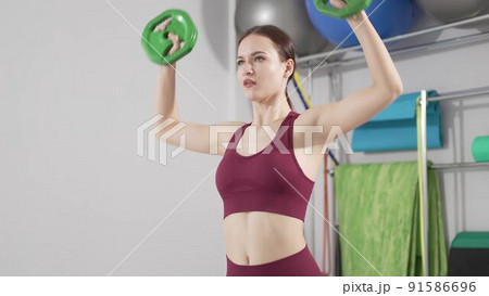 a beautiful and slender young woman does exercises with weights in the gym. a beautiful and slender young woman does exercises with weights in the gym. 91586696