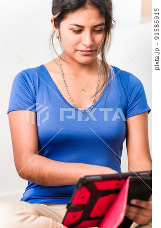 Bolivian young Hispanic woman doing school homework with digital tablet technology Bolivian young Hispanic woman doing school homework with digital tablet technology 91586915