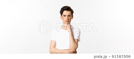 Image of attractive gay man in white t-shirt, having glitter on face and looking at camera serious, standing over white background Image of attractive gay man in white t-shirt, having glitter on face and looking at camera serious, standing over white background 91587006