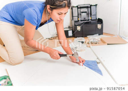 Latin Bolivian strong and independent success woman assembly and repair furniture with hammer. Latin Bolivian strong and independent success woman assembly and repair furniture with hammer. 91587054