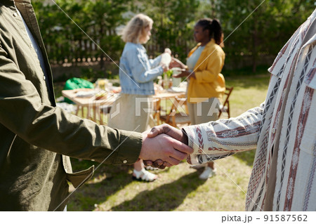 Handshake of two young interracial men greeting each other during outdoor party 91587562