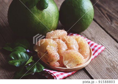 fresh green pomelo peeled and leaf frome pomelo tree , pummelo , grapefruit in summer tropical fruit  in thailand , pomelo fruit on wooden plate background 91588803